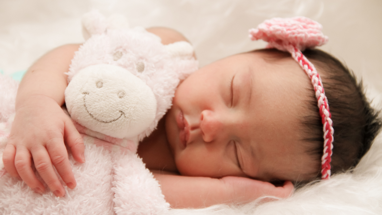 baby girl sleeping while holding her stuffed animal